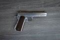 Stainless hand gun with brown hand grip is on the wooden floor