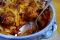 Stainless spoon in a ceramic casserole filled with baked pasta and meatballs Royalty Free Stock Photo