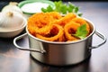 a stainless steel bowl filled with fresh made onion rings