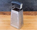 Stainless steel box-shaped four-sided grater on cutting board Royalty Free Stock Photo