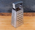 Stainless steel box-shaped four-sided grater on cutting board Royalty Free Stock Photo