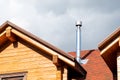 Stainless steel chimney pipe on roof of modern wooden beam cottage villa house. Home fireplace and heating exhaust system