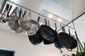 Stainless steel cookware , kitchenware set hanging on a rack on the wall, frying pans and saucepan in modern home Royalty Free Stock Photo