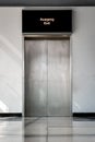 A stainless steel door of an elevator with refelcting tiles on the floor and a white wall Royalty Free Stock Photo
