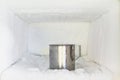 Stainless steel drinking water glass in freezer of a refrigerator. Ice buildup inside of a freezer walls. Royalty Free Stock Photo