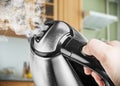 Stainless Steel Electric Kettle in hand on the background of the Royalty Free Stock Photo