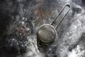 Stainless Steel Fine Mesh Strainer Colander Flour Sieve with Handle on dark background poudered with flour. Kitchenware Royalty Free Stock Photo