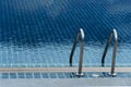 Stainless steel ladder beside the blue summer tile pattern swimming pool travel background