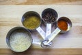 Stainless steel measuring cups holding assorted spices sitting on cutting board Royalty Free Stock Photo