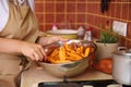 A bowl with slices of sweet potatoes seasoned with fragrant culinary herbs, in the hands of a housewife in chef& x27;s