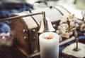 Stainless steel put out candle flame wick long handle candle snuffer bell with lit candle on esoteric background.