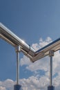 Stainless steel railing stairs from the outside of the building on a background of blue sky and beautiful clouds. Pipes, hinges, Royalty Free Stock Photo