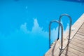 the stainless steel railing of the stairs by the pool with water Royalty Free Stock Photo