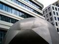 Stainless steel sculpture detail with modern style white and gray office buildings in the background