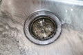 Stainless steel sink with drain stopper in and water running - closeup