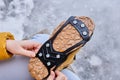 Pedestrian putting cleats on his shoes for extra traction during a winter walk during icy conditions.