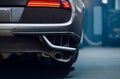 Stainless Steel Sports Car Exhaust Tip Close-Up with Showroom Bokeh Background. Royalty Free Stock Photo