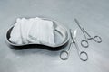 Stainless steel surgical scissors on the operating table. Kidney-shaped tray with pieces of gauze. Medical instruments for surgery Royalty Free Stock Photo