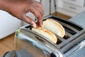 Stainless steel toaster toaster with toasted bread for breakfast inside with kitchen in the background. Hands of African American