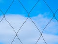 Abstract view of stainless steel mesh fence with clamps and blue sky background Royalty Free Stock Photo