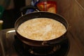 Stainless steel wok of cooking vermicelli kheer a stovetop surrounded by bags of assorted cereal