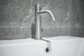 A tap or faucet on a white washbasin.Save water campaign