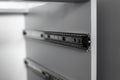 Stainless telescopic bayonet drawer slide guides, installed on a kitchen cabinet from gray chipboard. Accessories for Royalty Free Stock Photo