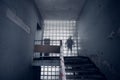 Staircase of an abandoned interior with a large glass wall behind which stands a blurred scary silhouette