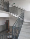 A staircase with forged cast-iron railings in a modern building illuminated with light from the windows. Interior staircase and Royalty Free Stock Photo