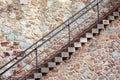 A staircase with iron railings along an old stone wall diagonally. Royalty Free Stock Photo