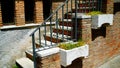 Staircase with marble steps and decorative railing of a brick building seen from below with flowerpots in the outside Royalty Free Stock Photo