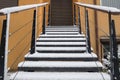 Staircase with metal steps and handrails dusted with drifts of white snow leading to closed door with blinds at entrance of house Royalty Free Stock Photo