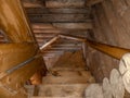 A staircase with a spiral descent, folded wooden steps, covered with a dark brown varnish of a traditional design in a Royalty Free Stock Photo