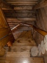 A staircase with a spiral descent, folded wooden steps, covered with a dark brown varnish of a traditional design in a Royalty Free Stock Photo