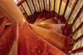 Staircase with spiral descent stacked wooden steps covered with dark brown varnish traditional construction Royalty Free Stock Photo