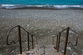 Staircase to beach. Blue water and stones on beach Royalty Free Stock Photo