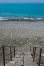 Staircase to beach. Blue water and stones on beach Royalty Free Stock Photo