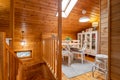 Stairs and dining room with table and chairs on the second floor of completely wooden house.