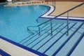 stairs down to the pool. Railings and stairs going down the blue water of an outdoor swimming pool Royalty Free Stock Photo