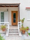 Stairs of an elegant house entrance with natural brown wood and glass door, decorated with potted plants. Royalty Free Stock Photo