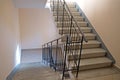 Staircase in the entrance with concrete steps and metal railing up and down against beige walls Royalty Free Stock Photo