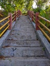 stairs made of cement with yellow iron pipe handles, red pillars with green trees growing around them Royalty Free Stock Photo