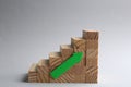 Stairs made of wooden blocks with green arrow on grey background. Career promotion concept Royalty Free Stock Photo
