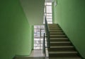 Stairs in a residential building. A wide-angle view of a modern flight of stairs against a green wall. Stairs in the modern lobby