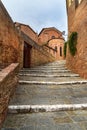 Stairs on the street Via Val di Montone and Basilica Maria dei Servi in Siena. Italy