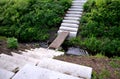 Stairs to the deep riverbed on both sides formed by light concrete stairs, which are also seats. in between is an improvised footb