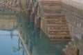 Stairs and wall of ocean fishing pier with reflections in water Royalty Free Stock Photo