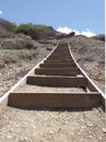 A stairway composed of a series of parallel cor-ten risers set into the earth. Rustic wood staircase structure perspective on dry