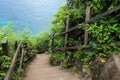 Stairway leading to the beautiful blue sea with natural wooden fence outdoor, surrounded by green trees Royalty Free Stock Photo