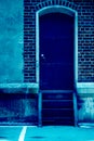 Stairway to old closed rusty metal door in red brick wall. Urban and industrial image. Vertical with copy space. Classic Royalty Free Stock Photo